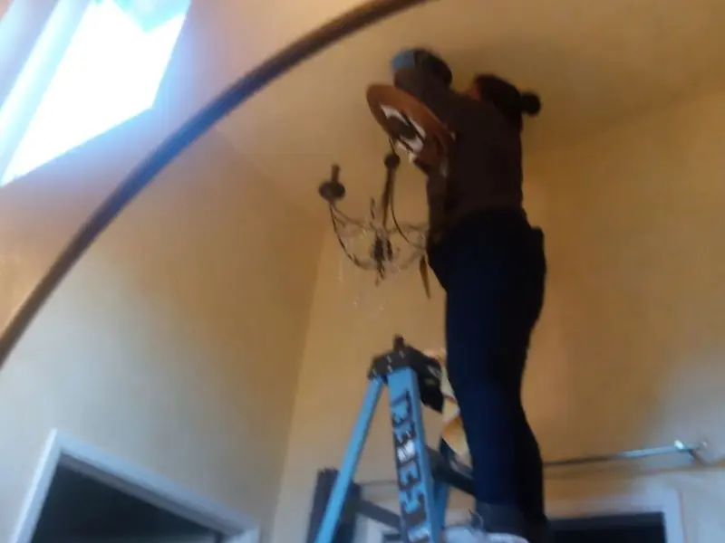 Electrician installing a chandelier in a Butler Beach residence